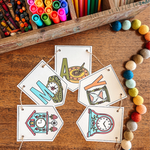 Load image into Gallery viewer, Colorful 'MAY' banner on a wooden surface with art supplies.