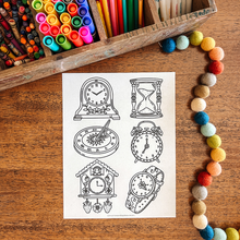 Load image into Gallery viewer, Sheet of clock-themed coloring pages on a wooden surface with art supplies.