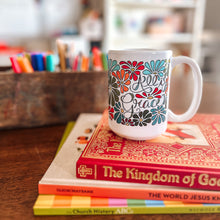 Load image into Gallery viewer, Mug with floral design and text "All is Grace" on a stack of books with a blurred bookshelf in the background