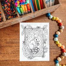 Load image into Gallery viewer, Coloring page with a squirrel illustration on a wooden surface with coloring supplies.