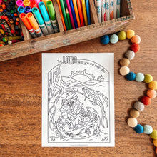 Load image into Gallery viewer, Coloring page with foxes under a tree, surrounded by colored pencils and markers on a wooden surface.