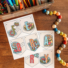 Load image into Gallery viewer, Colorful February banner on a wooden surface with art supplies.