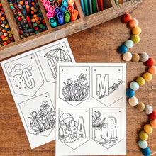 Load image into Gallery viewer, March themed coloring page banner on a wooden surface with art supplies.