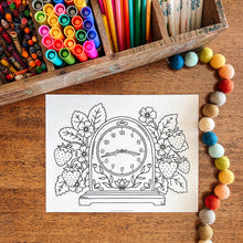 Load image into Gallery viewer, Coloring page with a clock design on a wooden table with art supplies.