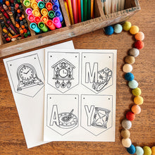 Load image into Gallery viewer, May coloring page banner with clock designs on a wooden surface with art supplies.