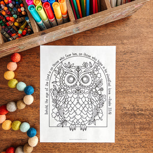 Coloring book with owl design on a wooden table with art supplies