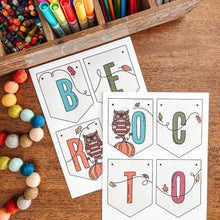 Load image into Gallery viewer, Colorful stationery items including crayons, markers, and colored pencils with October banner on a wooden surface.
