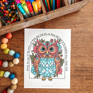 Coloring book with a colorful owl design on a wooden table with art supplies.