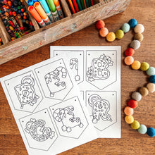 Load image into Gallery viewer, Coloring pages with shapes on a wooden surface next to art supplies.
