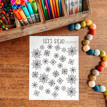 Load image into Gallery viewer, Reading tracker coloring page with snowflake patterns on a wooden surface.

