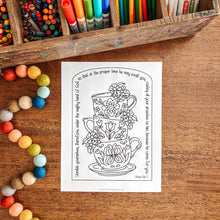 Load image into Gallery viewer, Coloring book page with teacup design on a wooden surface with art supplies.
