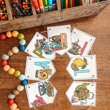 Load image into Gallery viewer, Colorful tea themed April banner on a wooden surface with art supplies.
