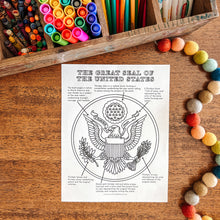 Load image into Gallery viewer, Coloring sheet of the Great Seal of the United States on a wooden surface with art supplies.
