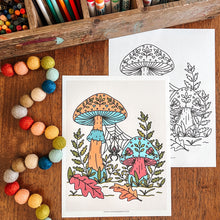 Load image into Gallery viewer, Two mushroom-themed coloring pages displayed on a wooden table, surrounded by colorful craft supplies including markers, paintbrushes, and pastel beads. One page shows a colored mushroom design, and the other shows a black-and-white line drawing.
