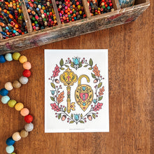 Load image into Gallery viewer, A white art print featuring a colorful, hand-drawn key and heart-shaped padlock illustration, styled on a wooden table with a wooden pencil box and colorful beads nearby.
