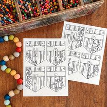 Load image into Gallery viewer, Two printable autumn-themed November banner sheets with fall illustrations, displayed on a wooden table alongside a wooden box of colorful crayons and a string of pastel beads.
