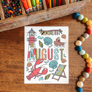 Colorful 'August' coloring page with lighthouse, boat, and other summer elements on a wooden surface with coloring supplies.