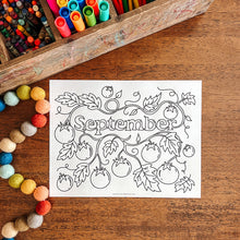Load image into Gallery viewer, Coloring page with &#39;September&#39; design on a wooden surface with art supplies.
