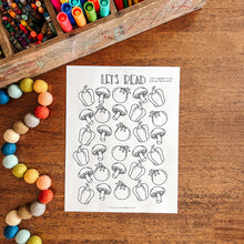 Load image into Gallery viewer, Coloring sheet with vegetable illustrations on a wooden surface with art supplies.
