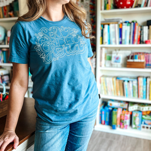 Person wearing a blue Soli Deo Gloria t-shirt with text in a room filled with bookshelves.